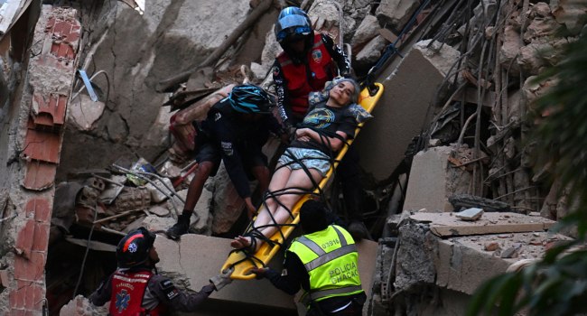 Rescue workers carry a person on a stretcher out of a collapsed building following an earthquake in